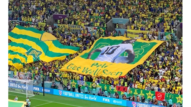 Créditos: Bolavip - Bandeira erguida pela torcida brasileira em homenagem a Pelé antes da partida contra Camarões, no Estádio Nacional de Lusail, em 02/12/2022