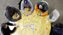 Amigos jogando poker em uma mesa redonda (Foto: Getty images)