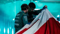 Foto oficial Aston Martin - Vettel e Stroll olhando o carro por baixo da bandeira da Grã-Bretanha