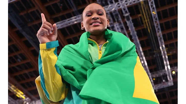 Rebeca Andrade enrolada com a bandeira do Brasil comemorando a medalha de ouro na ginástica artística (Getty Images)