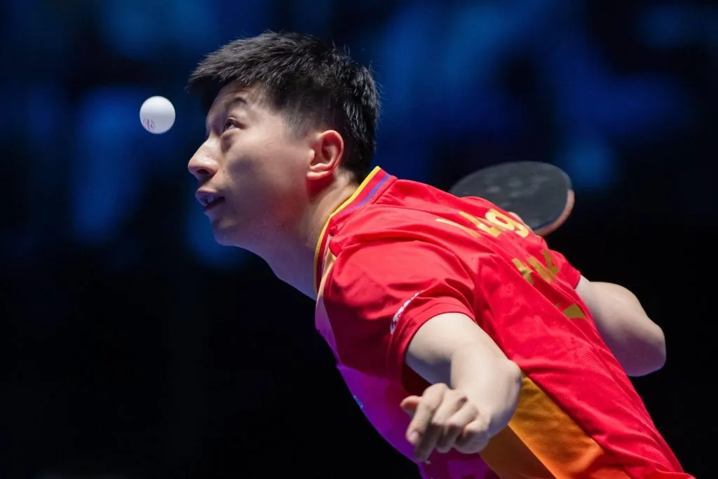 Foto de Ma Long, atleta de tênis de mesa da China, prestes a atingir bola. 