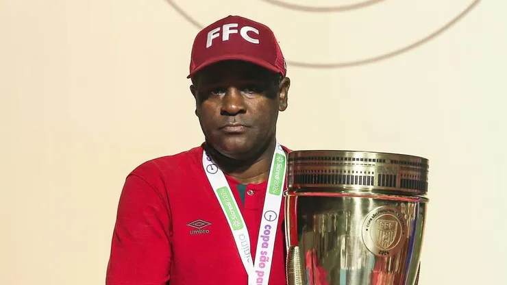 Visivelmente emocionado, PC Rodrigues, treinador das Meninas de Xerém, segura a taça da Copinha Feminina 2024 após a vitória sobre o Internacional no estádio do Canindé