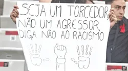 Cartaz: Seja um torcedor, não um agressor. Diga não ao racismo. Foto: Gabriel Machado/AGIF