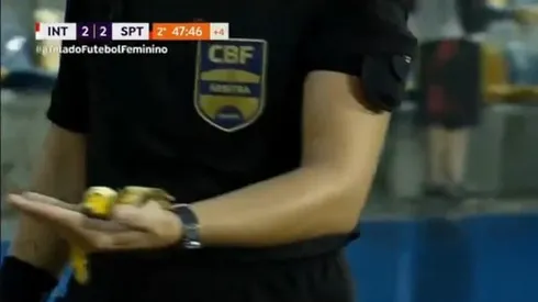 Quarta árbitra carrega pedaço de banana atirado pela torcida do Internacional no banco do Sport. Foto: Reprodução/TV Brasil