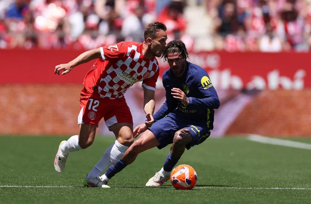 GIRONA, SPAIN – MAY 25: Arthur Melo of Girona FC runs with the ball under pressure from Rodrigo De Paul of Atletico de Madrid during the LaLiga match between Girona FC and Atletico de Madrid at Montilivi Stadium on May 25, 2025 in Girona, Spain. (Photo by Judit Cartiel/Getty Images)