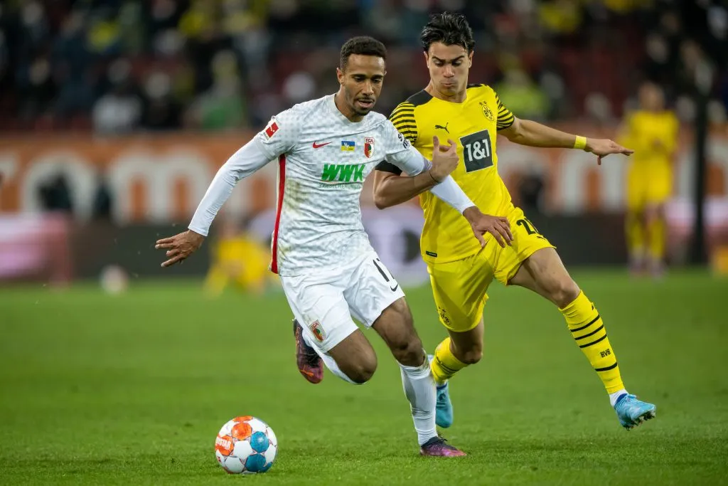 AUGSBURG, GERMANY – FEBRUARY 27: Noah Joel Sarenren Bazee of FC Augsburg and Reinier Carvalhod compete for the ball  during the Bundesliga match between FC Augsburg and Borussia Dortmund at WWK-Arena on February 27, 2022 in Augsburg, Germany. (Photo by Sebastian Widmann/Getty Images)