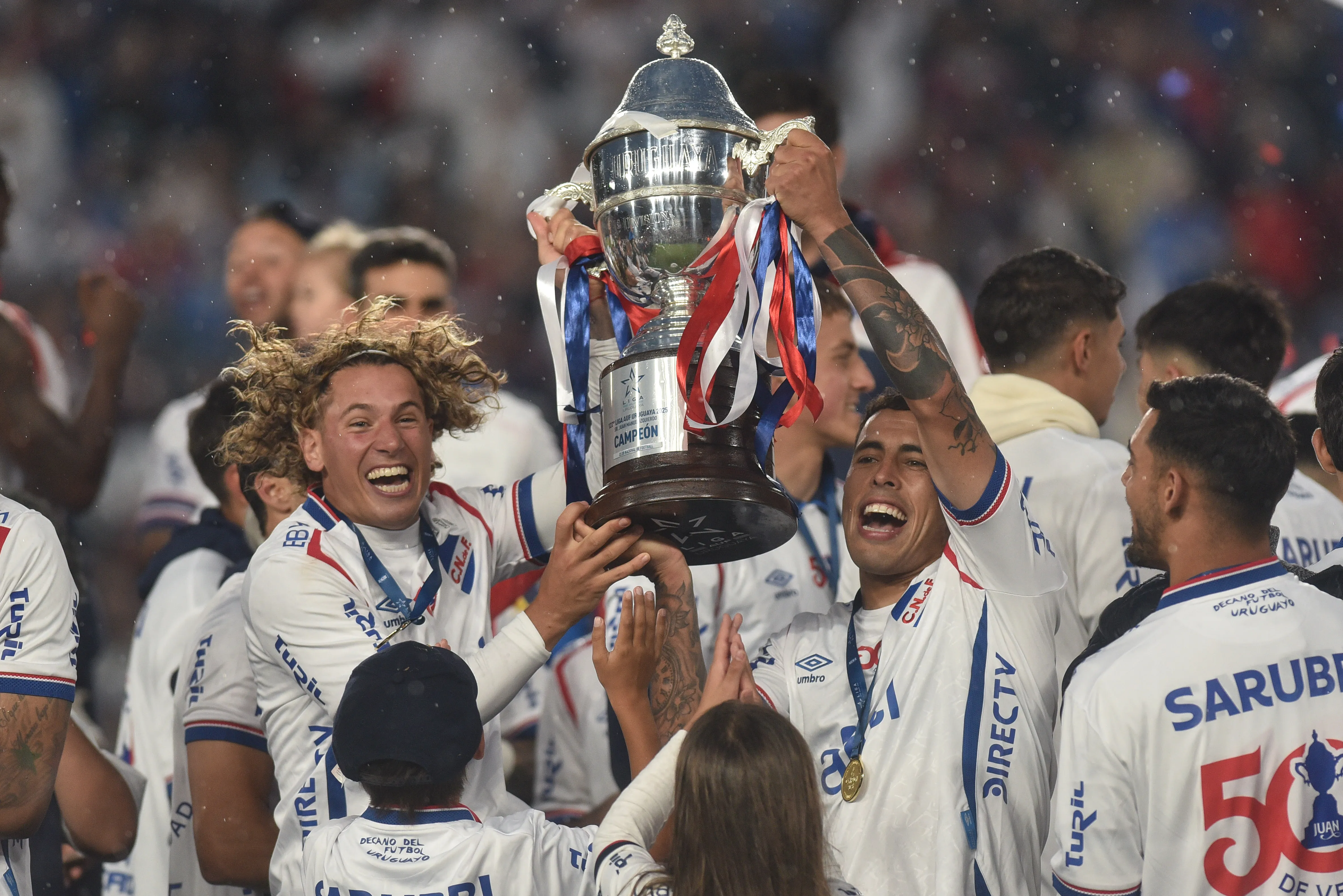 Luciano Boggio and Christian Oliva of Nacional celebrate lifting the trophy after winning the Campeonato Uruguayo 2025 second leg final match between Nacional and Peñarol at Gran Parque Central stadium on November 30, 2025 in Montevideo, Uruguay. (Photo by Guillermo Legaria/Getty Images)