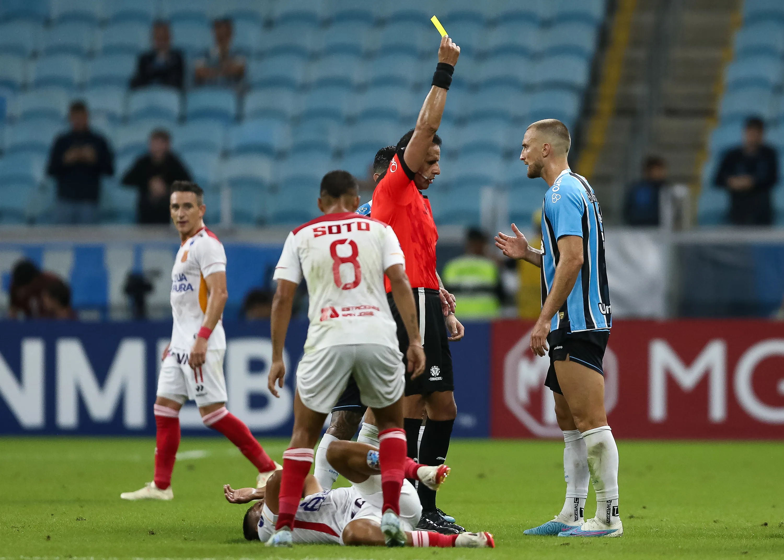PORTO ALEGRE, BRAZIL – APRIL 8: Referee Gery Vargas shows a yellow card to Rodrigo Ely of Gremio after fouling Aldair Vasquez of Atletico Grau during the Copa CONMEBOL Sudamericana Group D match between Gremio and Atletico Grau at Arena do Gremio on April 8, 2025 in Porto Alegre, Brazil. (Photo by Pedro H. Tesch/Getty Images)