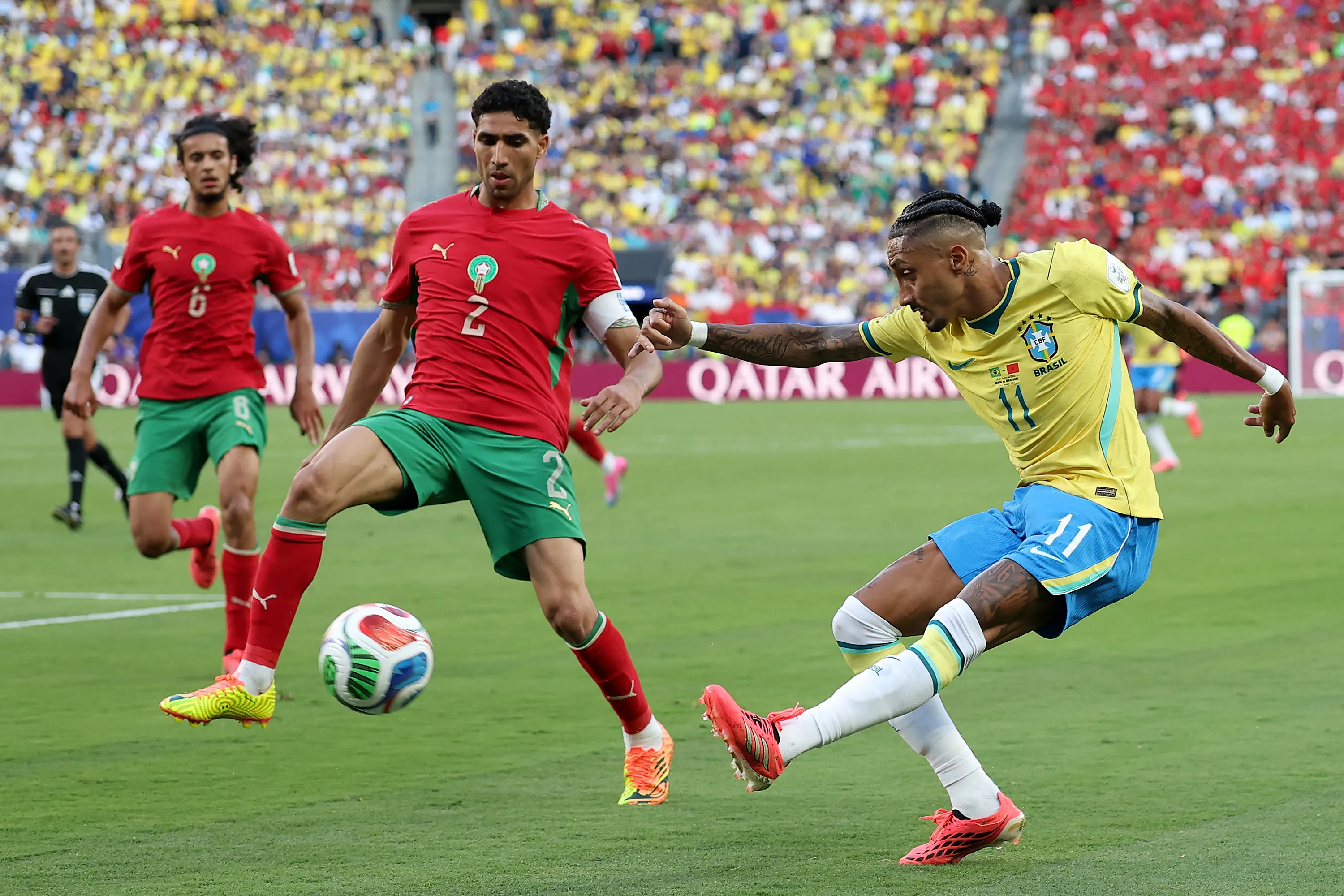 EAST RUTHERFORD, NEW JERSEY – JUNE 13: Raphinha #11 of Brazil crosses the ball against Achraf Hakimi #2 of Morocco during the FIFA World Cup 2026 Group C match between Brazil and Morocco at New York New Jersey Stadium on June 13, 2026 in East Rutherford, New Jersey. (Photo by Darrian Traynor/Getty Images)