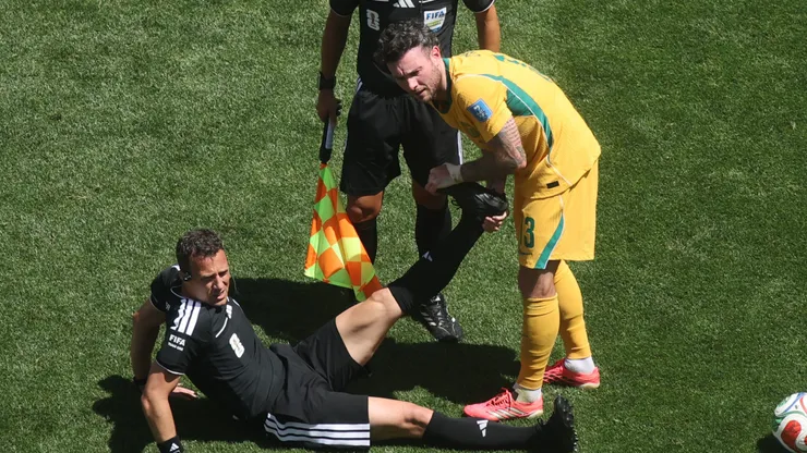 SEATTLE, WASHINGTON - JUNE 19: Referee Felix Zwayer is helped stretching his leg by Aiden O'Neill #13 of Australia after cramping during the FIFA World Cup 2026 Group D match between USA and Australia at Seattle Stadium on June 19, 2026 in Seattle, Washington. (Photo by Alex Grimm/Getty Images)