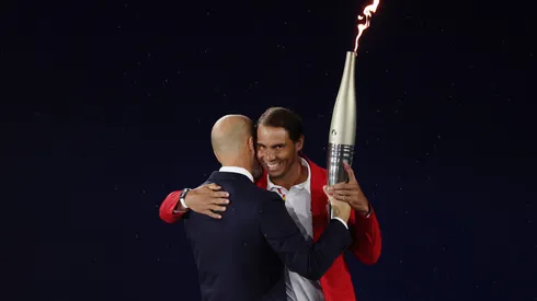Zinedine Zidane embraces Rafael Nadal as they exchange the Olympic Torch during the opening ceremony of the Olympic Games Paris 2024.