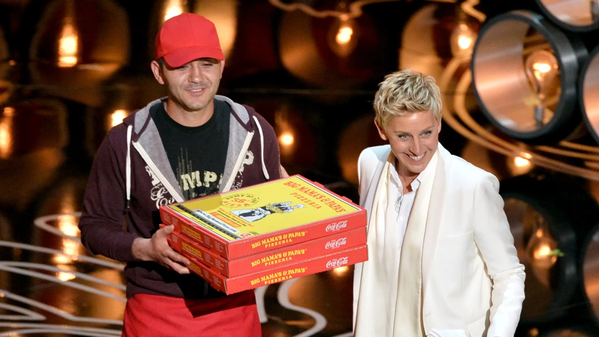 : Host Ellen DeGeneres (R) with pizza delivery man onstage during the Oscars at the Dolby Theatre on March 2, 2014 in Hollywood, California. (Photo by Kevin Winter/Getty Images)